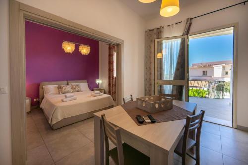 a bedroom with a bed and a table and a bed and a balcony at Villa Fontane Bianche in Fontane Bianche