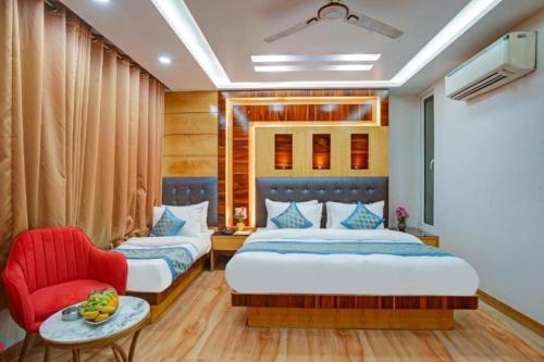 a bedroom with two beds and a red chair at Hotel Urban ECG Grand - Inn Near IGI Delhi Airport in New Delhi