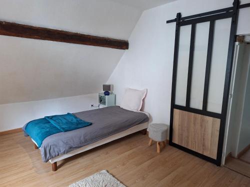 a bedroom with a bed with blue sheets and a window at La Maison du Cordonnier in Fréland