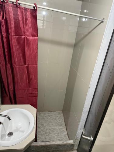 a bathroom with a sink and a red shower curtain at Hostal Mónaco in Machu Picchu