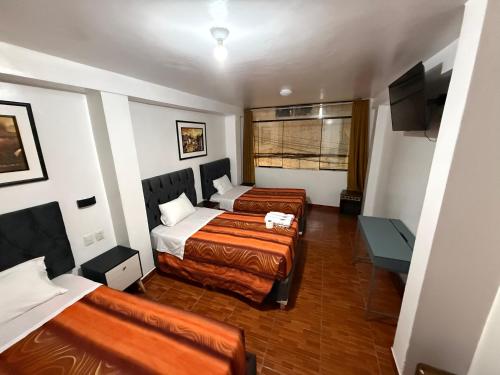 a hotel room with two beds and a television at Hostal Mónaco in Machu Picchu