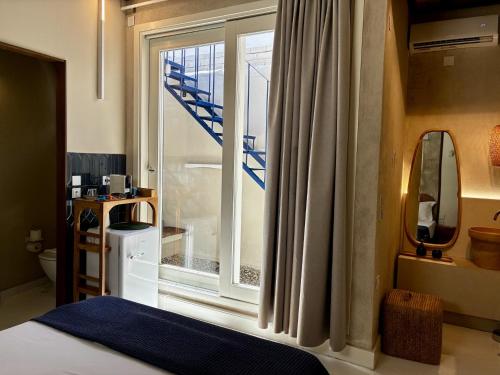 a bedroom with a bed and a window with a staircase at Synoikies by Oikieskiathos in Skiathos