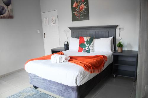 a bedroom with a large bed with an orange blanket at Divine Guest Lodge in Rustenburg