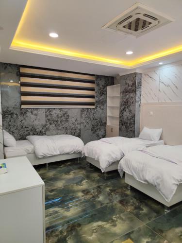 a bedroom with three beds and a floor with aitating at الربيعي للشقق الفندقية 200متر عن الحرم in Karbala