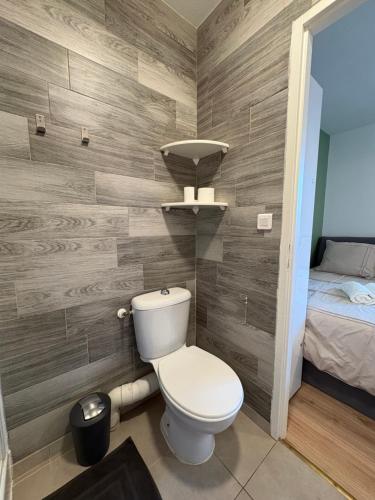 a bathroom with a toilet in a room with a bed at Cocon de la gare in Montélimar