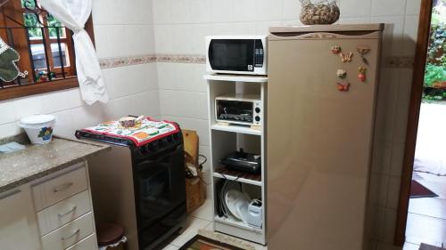 a kitchen with a refrigerator and a microwave at Refúgio do Azzi in Monte Verde
