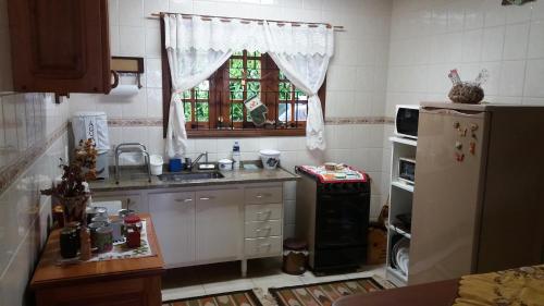 a kitchen with a sink and a refrigerator and a window at Refúgio do Azzi in Monte Verde