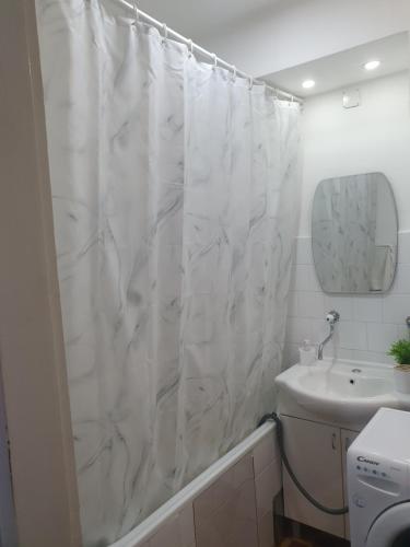a bathroom with a white shower curtain and a sink at Apartman Centar Lux in Pirot