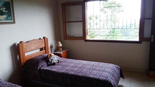 a teddy bear sitting on a bed in a bedroom at Refúgio do Azzi in Monte Verde