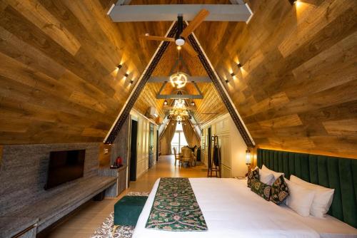 a bedroom with a large bed and a wooden ceiling at Asal Riverside Pahalgam in Pahalgām