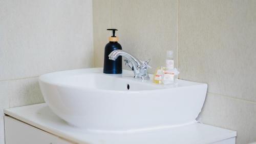 a bathroom sink with a soap dispenser and a bottle on it at Divine Guest Lodge in Rustenburg