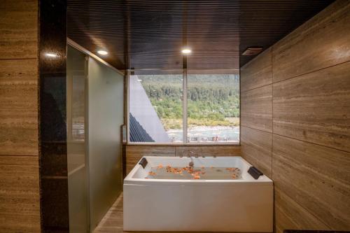 a bath tub in a room with a large window at Asal Riverside Pahalgam in Pahalgām