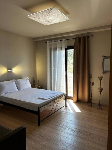 a bedroom with a bed and a large window at VILLA KTIMA MELINA Pelio ΒΙΛΑ ΜΕ ΠΙΣΙΝΑ ΒΟΛΟΣ ΠΗΛΙΟ in Álli Meriá