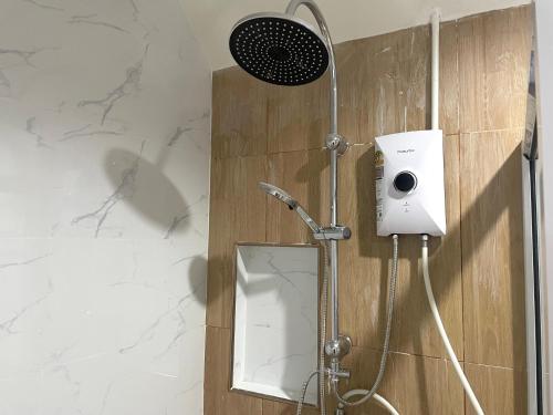 a shower with a shower head and a mirror at The Kanee Hostel in Nakhon Phanom