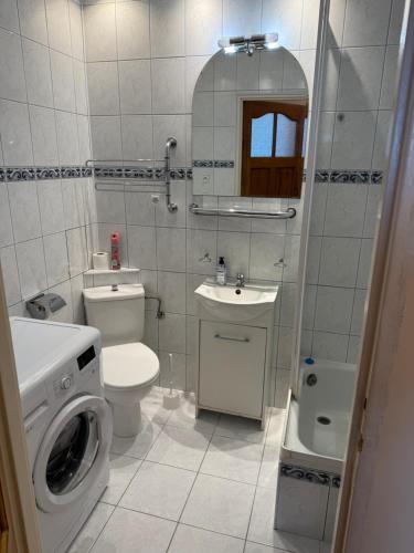 a bathroom with a toilet a sink and a washing machine at Daniel Apartment in Reda