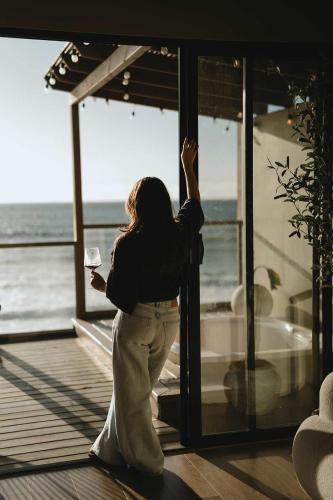 a woman standing in front of a window holding a wine glass at Kasa Dharma an oceanfront House in El Suazal