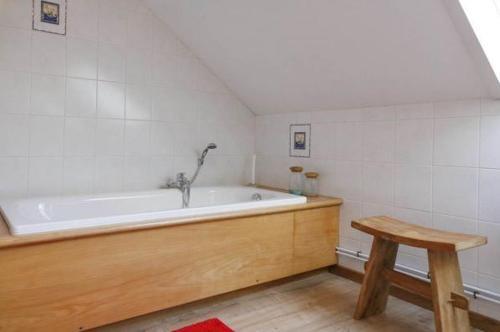 y baño con bañera y taburete de madera. en Val du Roannay, en Stavelot
