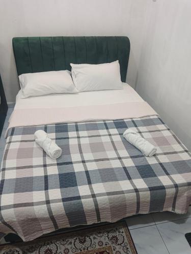 a bed with a plaid blanket and white pillows on it at Tiny House Anjung Batu Tangkak in Tangkak