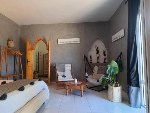 a bedroom with a bed and a chair and a table at Villa Daba By Zelia in Ghazoua