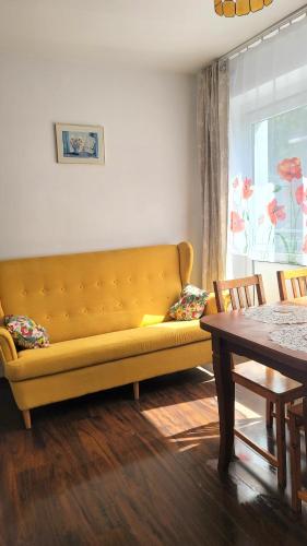 a yellow couch in a living room with a table at Happy One Park Apartment in Świdnica