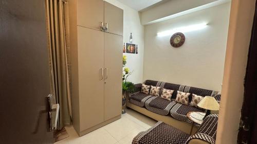 a living room with a couch and a clock on the wall at THE NEST - Kingdom in Ghaziabad