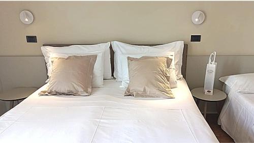 a bed with white sheets and pillows in a bedroom at Hotel Estense in Gatteo a Mare
