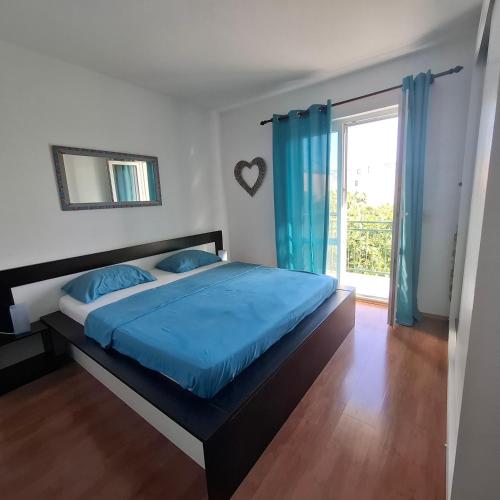a bedroom with a bed with blue sheets and a window at Apartment Računica in Vodice