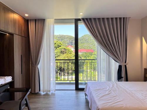 a bedroom with a bed and a view of a balcony at Hidden Green Hotel Tam Coc in Vũ Lâm