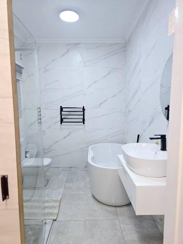 a white bathroom with a tub and a sink at Stegor Suites in Maun