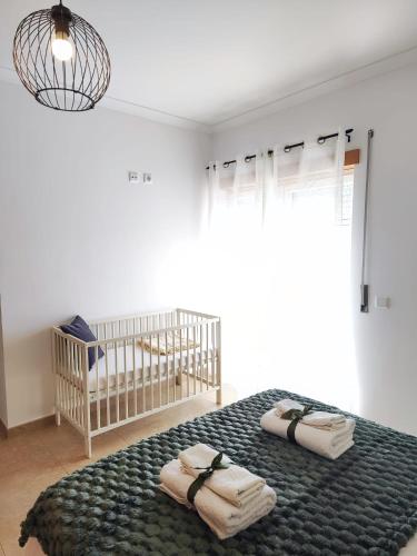 a bedroom with a crib and two towels on a bed at AO - Tina House Ferrel in Ferrel