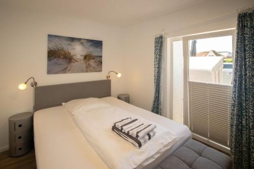 a bedroom with a bed and a large window at Haus Roseneck App.2 in Hörnum