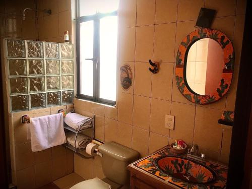 a bathroom with a toilet and a sink and a mirror at Hotel Departamentos Suites in Guanajuato