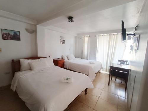 a hotel room with two beds and a desk at El Balcon Hostal in Ayacucho