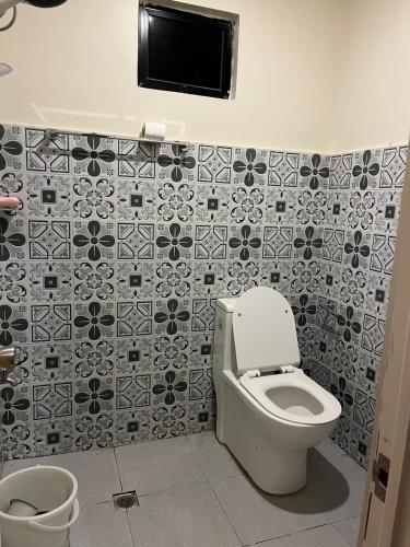 a bathroom with a toilet and a tiled wall at Mystical Hidden Farmhouse in Mahinog