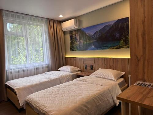 two beds in a hotel room with a painting on the wall at GuestHouse-Medeu in Almaty