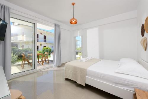 a white bedroom with a bed and a large window at VILLA TOSTi & VILLA JOY in Skala Rachoniou
