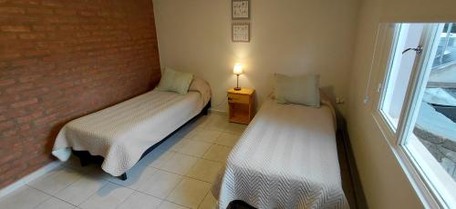 two beds in a small room with a window at CALAFATE CENTER APARTS in El Calafate