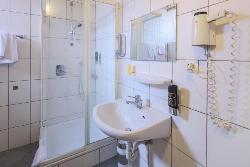 a white bathroom with a sink and a shower at Hotel Starkenburger Hof in Heppenheim an der Bergstrasse