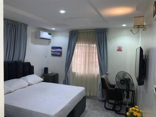 a bedroom with a bed and a chair and a window at Pointax Apartment Lekki in Ilado