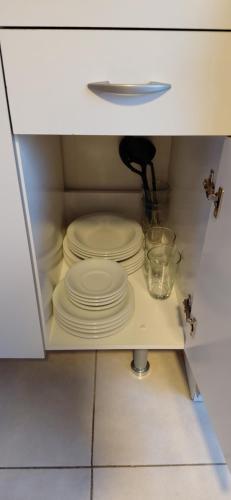 a cabinet filled with white plates in a kitchen at CALAFATE CENTER APARTS in El Calafate