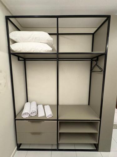a book shelf with shoes and a bed at Apartamento Centro Campina Grande in Campina Grande
