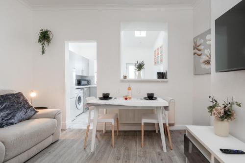 a white living room with a table and a couch at Denton Luxury Home - Sleep 8 - Speedy Wi-Fi - Free On-Site Parking in Denton