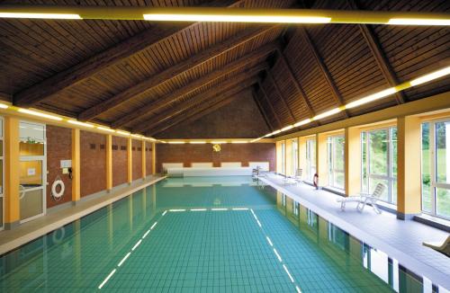 a large swimming pool with green tiles in a building at Hotel Fröbelhof in Bad Liebenstein