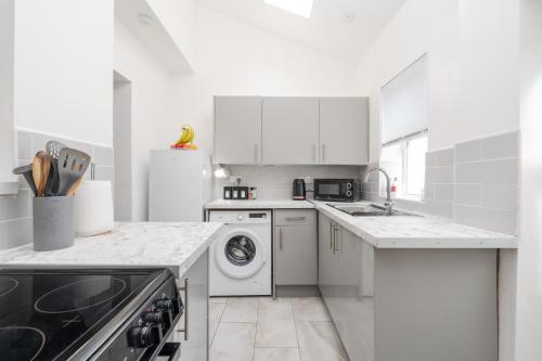 a kitchen with white cabinets and a washer and dryer at Denton Luxury Home - Sleep 8 - Speedy Wi-Fi - Free On-Site Parking in Denton
