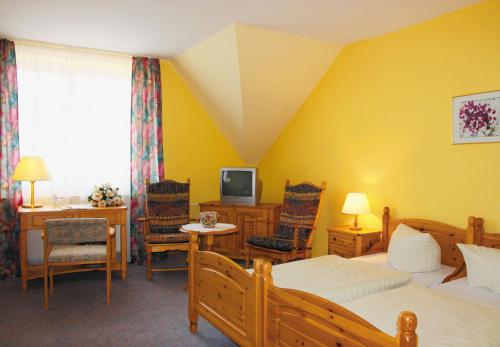 a room with two beds and a desk and a television at Hotel Fröbelhof in Bad Liebenstein