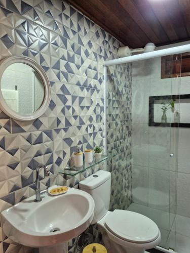 a bathroom with a toilet and a sink and a mirror at Luz Residence suíte in Cabo Frio