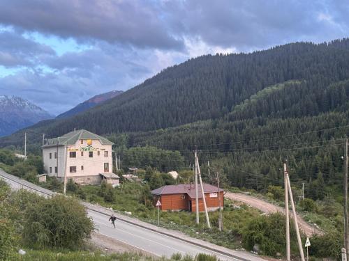a person walking down a road next to a mountain at Жайсан in Karakol