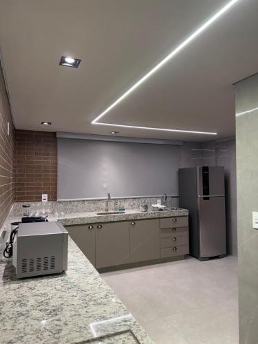 a large kitchen with a refrigerator and a counter at Apartamento Boutique Cheia de Graça 304 in Divinópolis