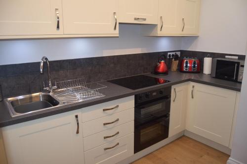 uma cozinha com armários brancos e um lavatório em Malvern Stables em Great Malvern