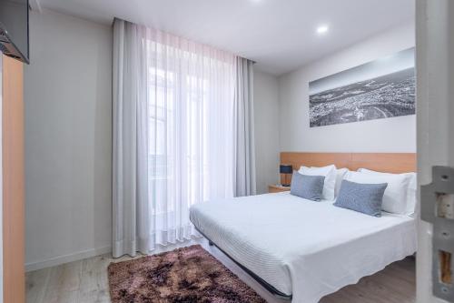 a bedroom with a white bed and a large window at CasAmalia 54 in Viana do Castelo
